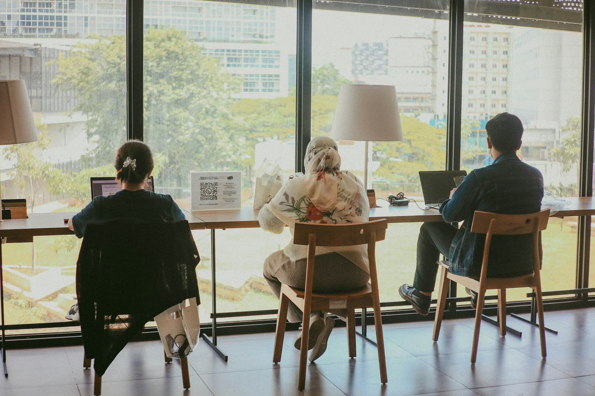 Two people working at a table, backlit by a window
